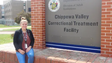 female student seated in front of signage at the Chippewa Valley Correctional Treatment Facility